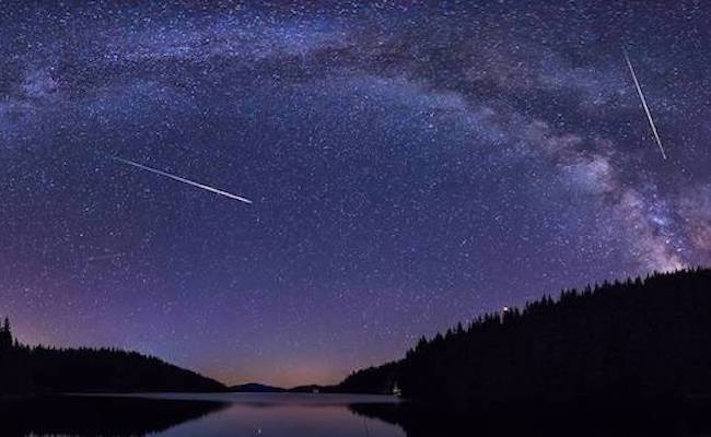 Algunas perseidas cruzan el cielo nocturno sobre un paisaje montañoso de Bulgaria. Al fondo, la Vía Láctea. / Adobe Stock